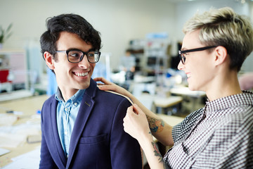 Young businessman talking to his tailor during alterations in workshop