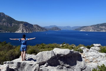 Naklejka premium Girl in a blue dress looking beautiful sea views in the resort moselkern,surrounds the resort town of Marmaris. Summer landscape