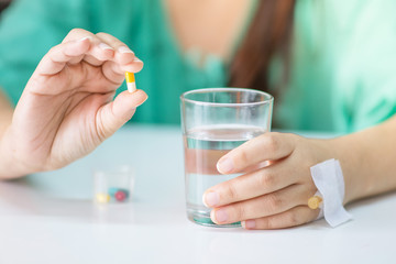 The patient handles the cup to prepare to take some medicine and a glass of water.