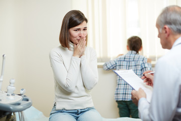 Fototapeta premium Young woman crying while listening to doctor advice and precriptions after examine