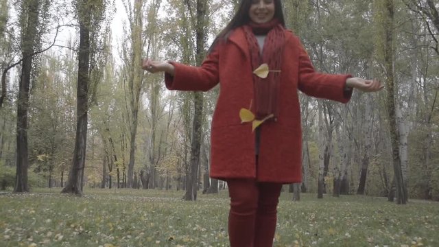 Young woman tossing up leaves in autumn forest park Full HD video. Overweight fat female playing, leaves falling. Camera moving to girl 