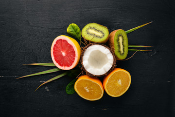 Fresh Tropical Fruits. Coconut, orange, kiwi and grapefruit. On a wooden background. Top view. Free space for text.