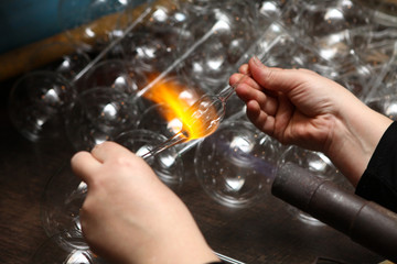 Factory of Christmas toys. The worker blows out the glass. The burner melts the glass. Decoration of a Christmas tree toy. Handmade. Manufacture of fur-tree toys. Many beautiful glass beads.