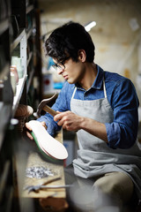 Naklejka premium Young footwear repairman doing his work in his own workshop