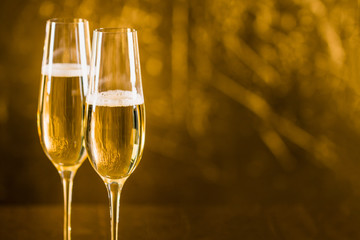 Two glasses of champagne in golden tone with copy space.
