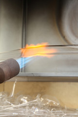 Factory of Christmas toys. The worker blows out the glass. The burner melts the glass. Decoration of a Christmas tree toy. Handmade. Manufacture of fur-tree toys. Many beautiful glass beads.