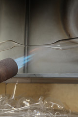 Factory of Christmas toys. The worker blows out the glass. The burner melts the glass. Decoration of a Christmas tree toy. Handmade. Manufacture of fur-tree toys. Many beautiful glass beads.