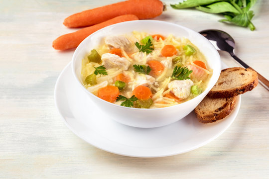Chicken soup with noodles, bread, and copy space