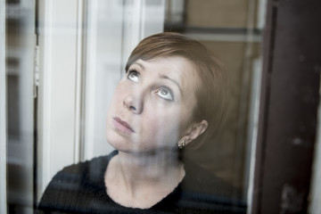 dramatic close up portrait of young beautiful woman thinking and  feeling sad suffering depression at home window looking depressed