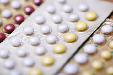Close up Oral contraceptive pill on pharmacy counter with colorful pills strips. Contraception reduces childbirth concept.