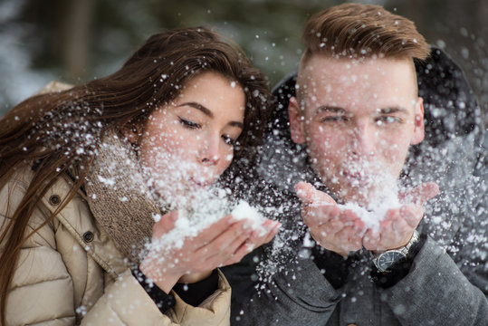 Romantic couple blowing snow away