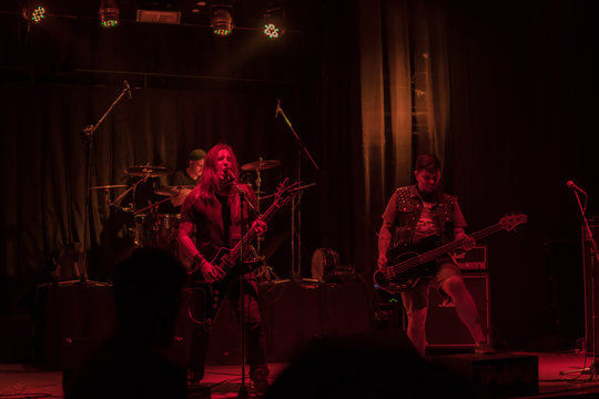 Singer with a guitar sings into a microphone to the accompaniment of his musical group