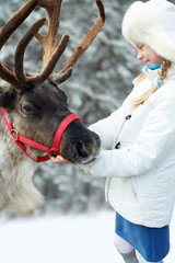Happy little girl hugging her reindeer. Winter playtime.