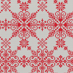 Knitted seamless pattern of white snowflakes on a red background