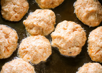 Meat cutlets during frying process in the pan, close up, top view