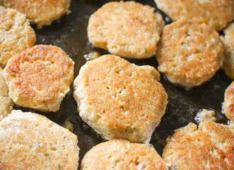Meat cutlets during frying process in the pan, close up, top view