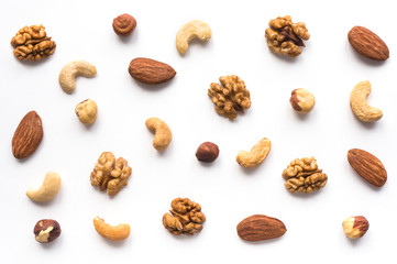 Isolated nuts pattern backdrop. Walnut, cashew, almond and hazelnut on white background. Top view. 