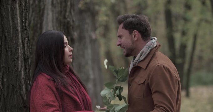 Couple quarreling in autumn forest park 4k video. Young angry overweight woman hits with flower in man face and goes away. Fail romance date. Love story concept