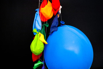 Some burst, deflated balloons and one inflated balloon hanging on threads.