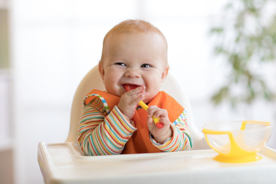 happy baby boy waiting for food with spoon at table