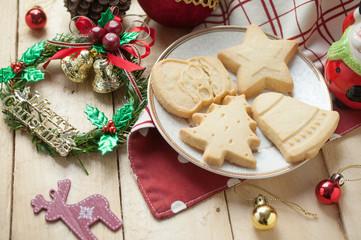 Tasty Christmas cookie on white plate with Christmas decoration on wooden background