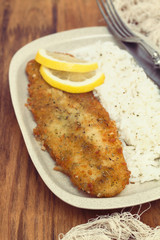 fried fish with lemon and boiled rice on dish