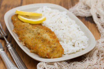 fried fish with lemon and boiled rice on dish