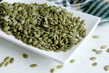 Raw pumpkin seeds. Green unshelled pumpkin seed in plate.