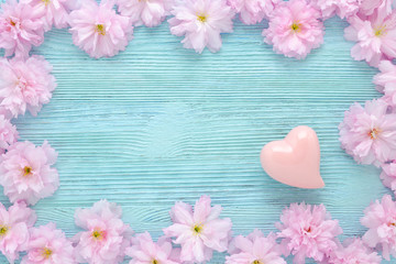 pink cherry fresh flowers frame with a heart on blue wooden background flat