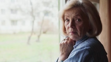 Close-up of sad old woman turning her head and looking into the camera