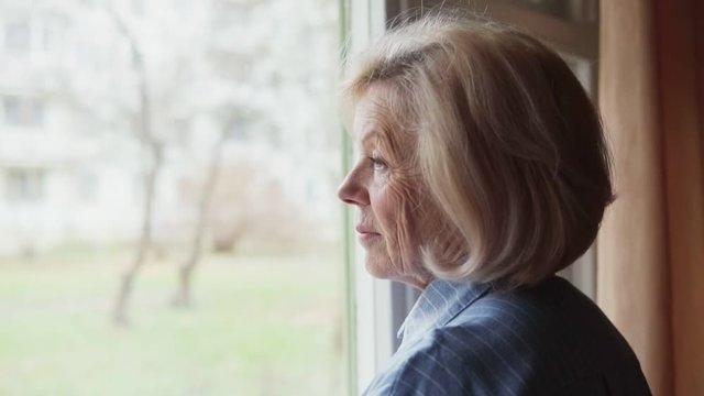 Sad old woman looking out the window