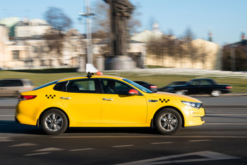Yellow taxi car in motion on city street
