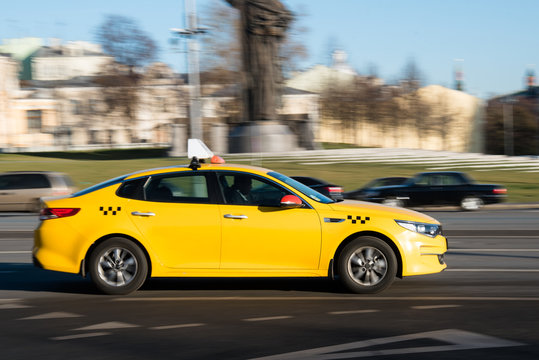 Yellow taxi car in motion on city street © VladFotoMag