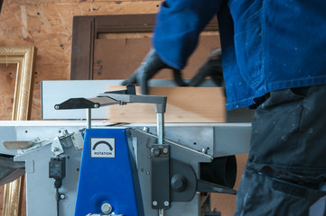 Carpenter working on the wood planer in a small workshop.