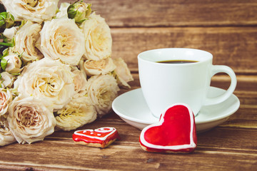Valentine's day. Wedding . A Cup of coffee and two gingerbread heart on a background of roses.
