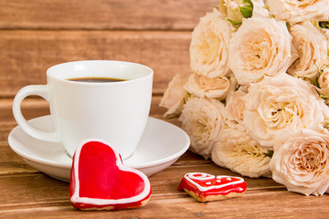 Valentine's day. Wedding . A Cup of coffee and two gingerbread heart on a background of roses.