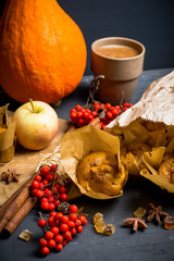 Muffins with pumpkin and apples on the rustic background with autumn decorations. Selective focus.