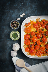 Garlic herbs roasted tomatoes with on dark blue stone background. Top view, copy space. 