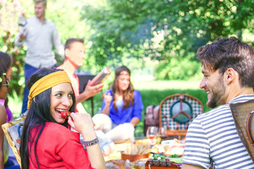 Group of happy friends making a picnic bbq in a park outdoor - Young people having a barbecue party enjoying food and drinks together - Friendship, lifestyle, youth concept - Focus on woman face