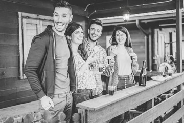 Happy friends enjoying a meeting drinking red wine and eating together in the backyard - Young people having fun with drinks standing outside home - Friendship, lifestyle, youth concept