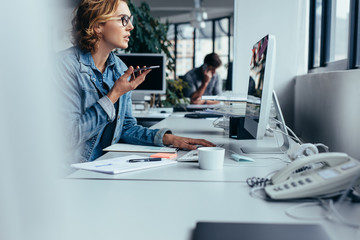 Businesswoman talking on phone and working on computer