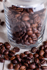 Coffee beans or grain in jar on white wooden background.