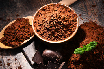 Composition with bowl of cocoa powder on wooden table