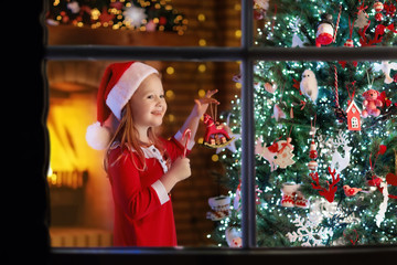 Child at Christmas tree and fireplace on Xmas eve