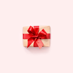 Gift box with red ribbon on pink background