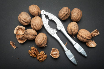 Spilled walnuts and nutcracker on a black background. Organic protein and omega 3.