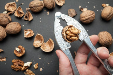 Fototapeta na wymiar Nutcracker with a chopped walnut in a man's hand on a black background.