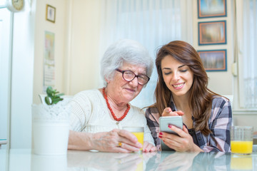 Young woman showing something on mobile phone to grandmother.