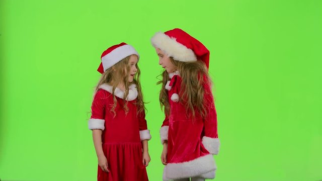 Two children girls swear and argue, they are in colorful costumes. Green screen. Slow motion