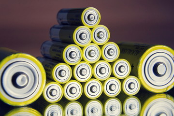 Stack of yellow AA batteries close up abstract color background